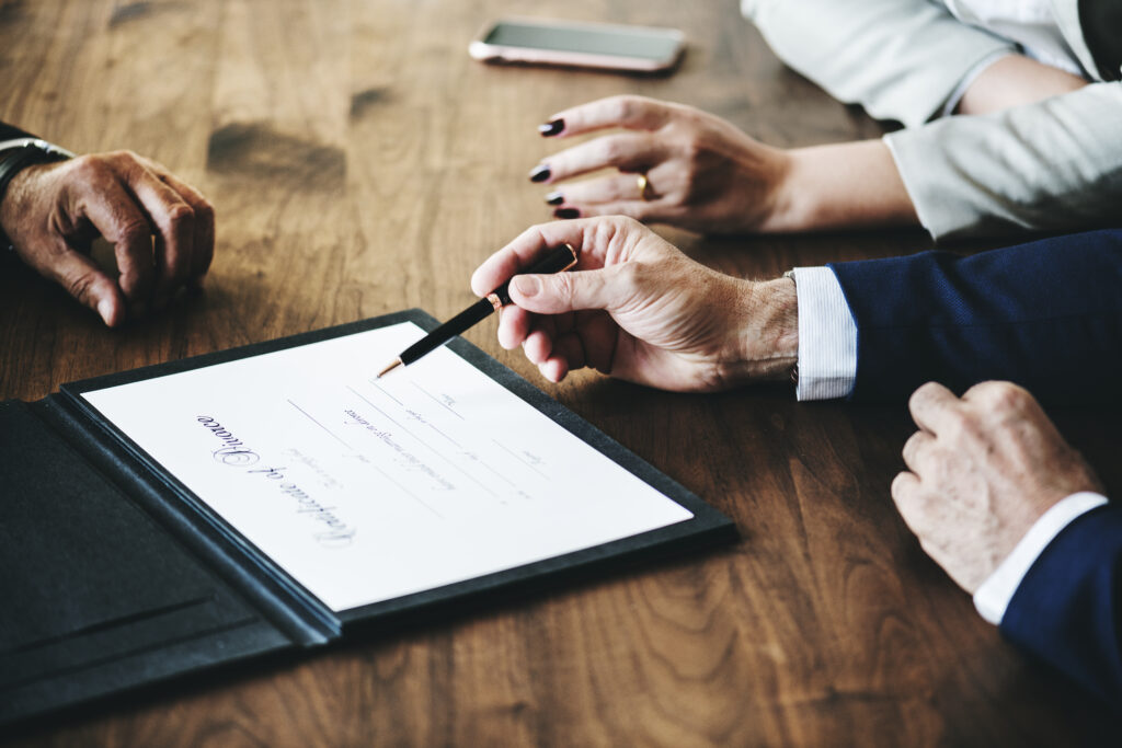 Two people are sitting at a table with papers and pens.