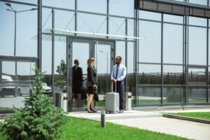 A man and two women are standing outside of an airport.