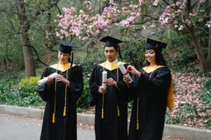 Three graduates in caps and gowns standing next to each other.