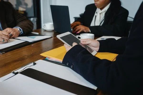 A person sitting at a table with two laptops.