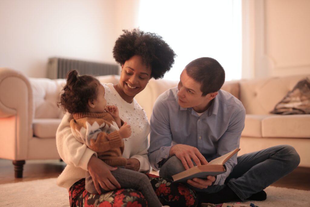 A man and woman sitting on the floor with a child.